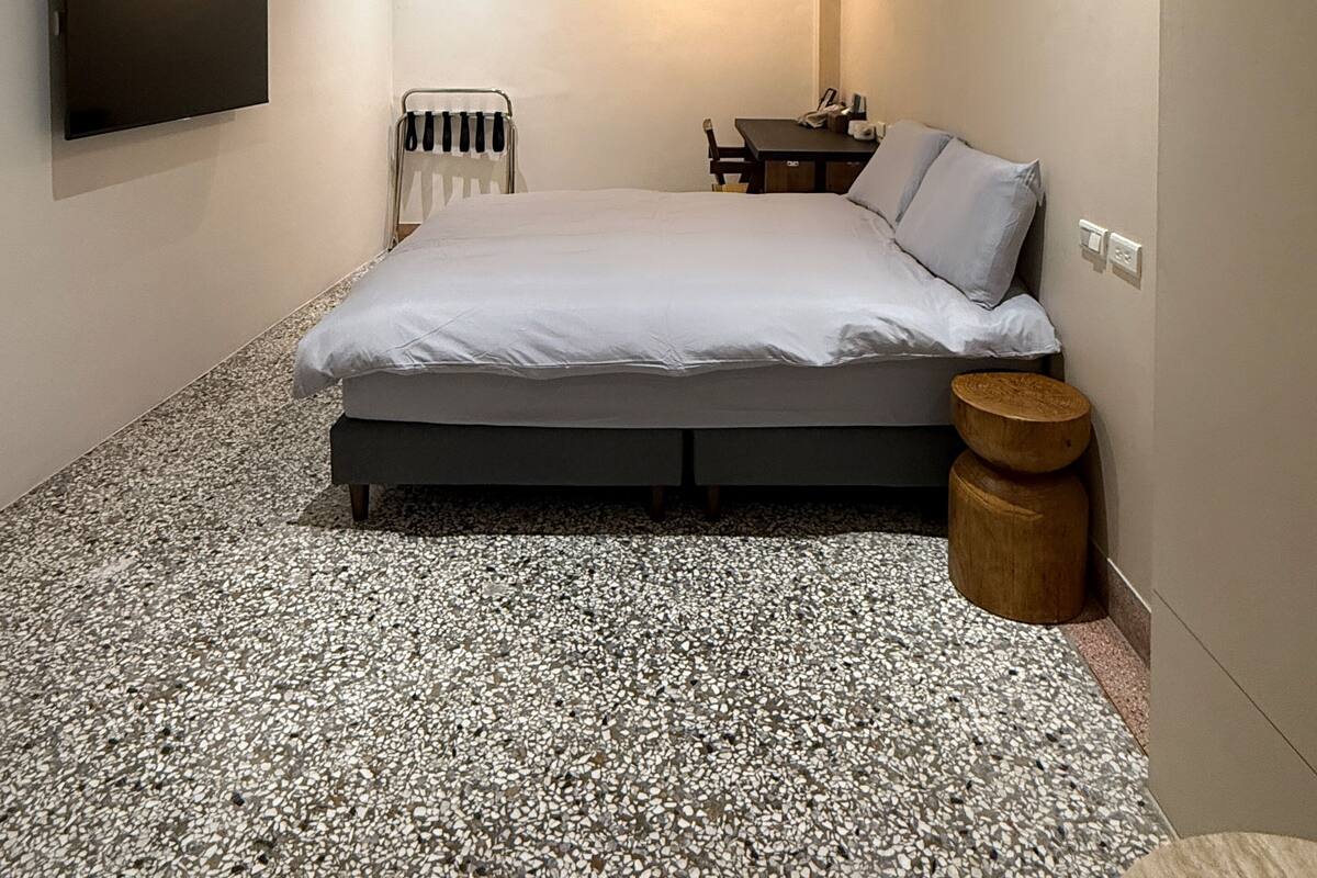 Un dormitorio moderno con cama, televisión, escritorio y lámpara colgante.