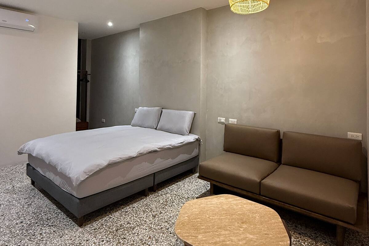 Un dormitorio moderno con cama, sofá y una mesita.