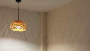 Una habitación pequeña y moderna con escritorio, silla y una lámpara colgante.