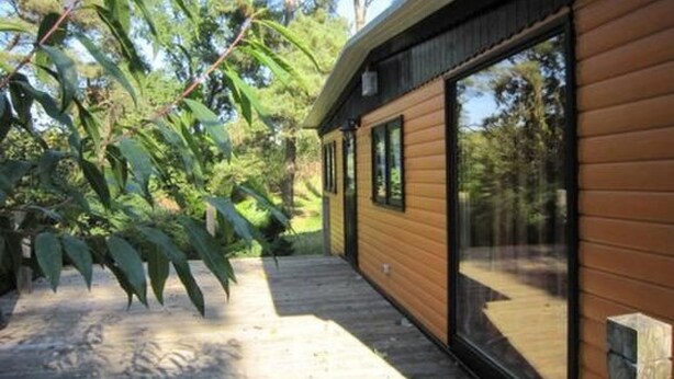 A modern wooden cabin with large sliding glass doors, surrounded by lush greenery. - Ferienhäuschen am Strandbad Lychen, Bungalow by Interhome (Lychen)