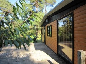 A modern wooden cabin with large sliding glass doors, surrounded by lush greenery. - Ferienhäuschen am Strandbad Lychen, Bungalow by Interhome (Lychen)