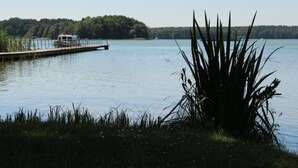 A calm lake with a dock extending into the water, surrounded by greenery and a clear sky. - in Hohenlychen mit Grill, Loggia 1 by Interhome (Lychen)