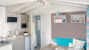 A modern kitchen with a microwave, stove, and sink. There is a dining area with a table and chairs, and a blue sofa. - in Hohenlychen mit Grill, Loggia 1 by Interhome (Lychen)