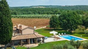 Una villa con piscina, rodeada de olivos y vistas al campo.