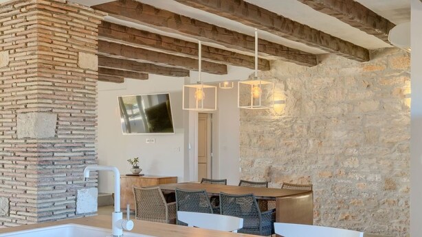 Una cocina moderna con una pared de acento de piedra, vigas de madera e iluminación colgante.