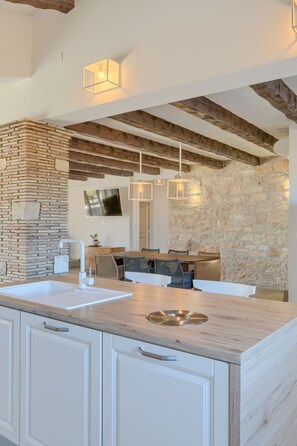 Uma cozinha moderna com parede de pedra decorativa, vigas de madeira e iluminação pendente.