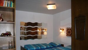 A bedroom with two beds, a bookshelf, a decorative wall piece, and a ceiling light. - Sonnenbichl Wh 102 by Interhome (Oberstdorf)