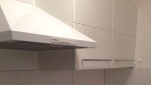 A kitchen with white cabinets, a stainless steel sink, a black countertop, and a built-in range hood. - Sonnenbichl Wh 102 by Interhome (Oberstdorf)