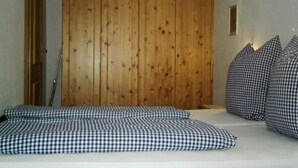 Un dormitorio con un armario de madera, una cama con ropa de cama a cuadros y una mesita de noche pequeña.