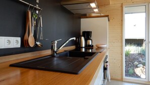 A modern kitchen with a black countertop, stainless steel sink, and a coffee maker. - "Gartenglück" by Interhome (Alt Jassewitz)