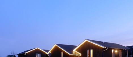 A modern building with a unique roofline and illuminated edges, situated in a residential area.