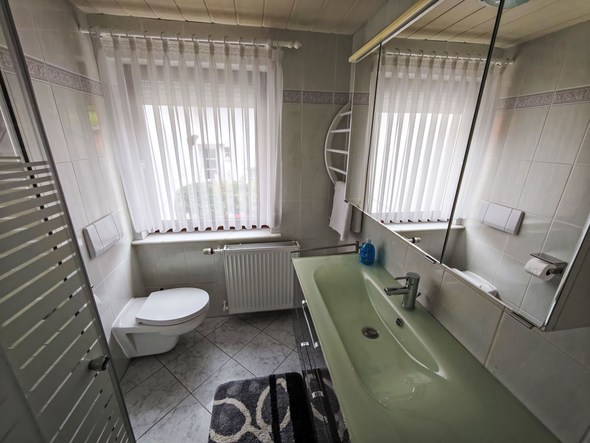 Un bagno con il water, un lavandino e una finestra con tende.