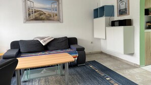 A small, modern living space with a sofa, a wooden table, and a colorful rug. - Hans am Klostersee by Interhome (Dargun)