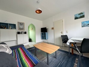 A compact living space with a sofa, a small wooden table, a TV, and a dining area. - Hans am Klostersee by Interhome (Dargun)