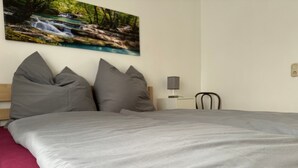 A bedroom with a bed, pillows, a nightstand, a lamp, and a painting of a waterfall. - Hans am Klostersee by Interhome (Dargun)