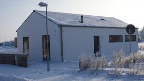 En etagers bygning med skråt tag, lille veranda og parabolantenne.