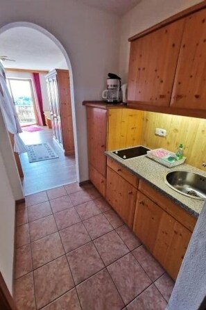 A kitchen with wooden cabinets, a sink, and a countertop. - Wohnung in Traumlage bei Sankt Englmar by Interhome (Sankt Englmar)