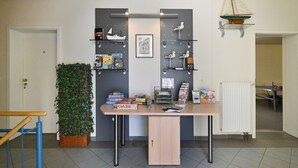 Una habitación con escritorio, estanterías llenas de libros y juegos, una planta y un modelo de barco.