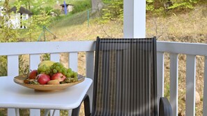 Un área de estar al aire libre con una silla de mimbre y una mesa con un frutero.