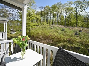 A white outdoor seating area with a table and chairs, overlooking a forested landscape. - Villa Celia Sellin by Interhome (Ostseebad Sellin)