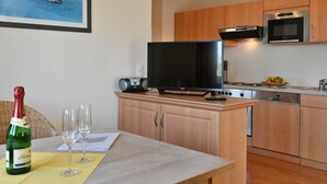 Een moderne keuken met houten kastjes, een ingebouwde oven, magnetron en een eethoek met een tafel gedekt voor twee personen.