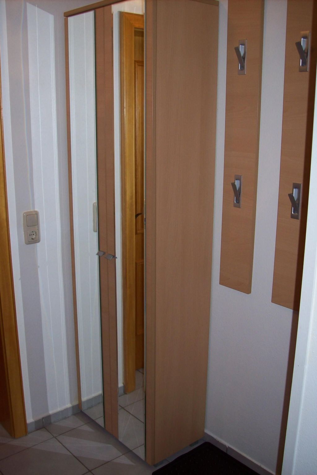 A room with a sliding door, a wooden door, and a wall-mounted light switch.