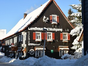Un bâtiment traditionnel en bois, sur lequel on peut lire l’inscription « Landhaus WeiWolgang » et « GALERIE RESTAURANT », indiquant qu’il s’agit d’un établissement comprenant une galerie et un restaurant.