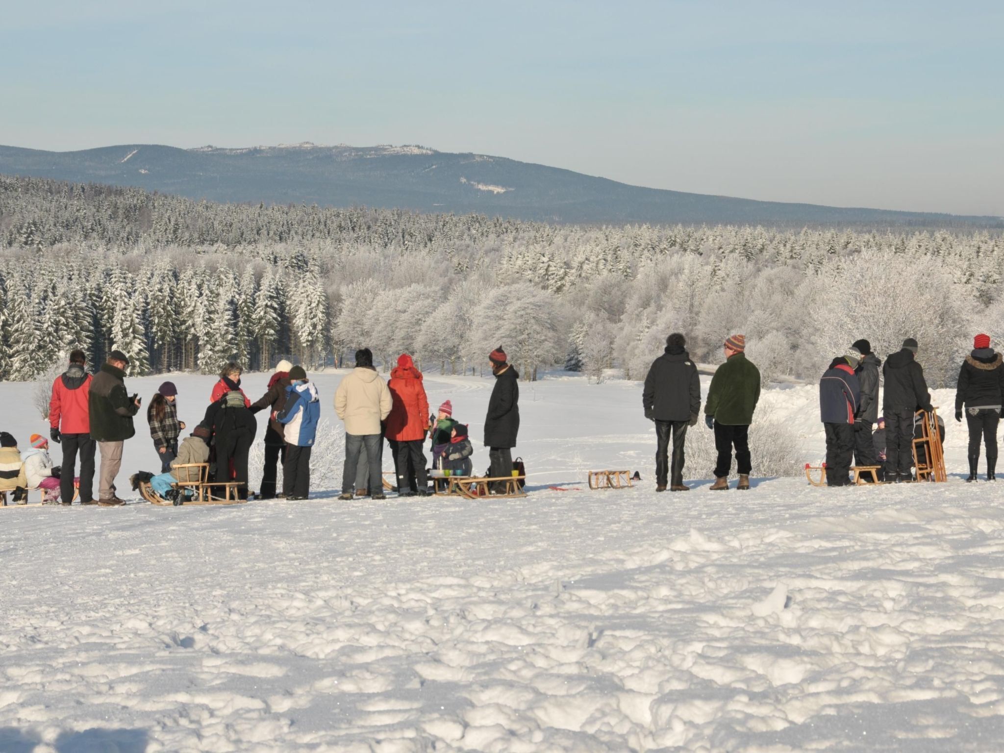 A group of people in a snowy outdoor setting with sleds and a sled track.