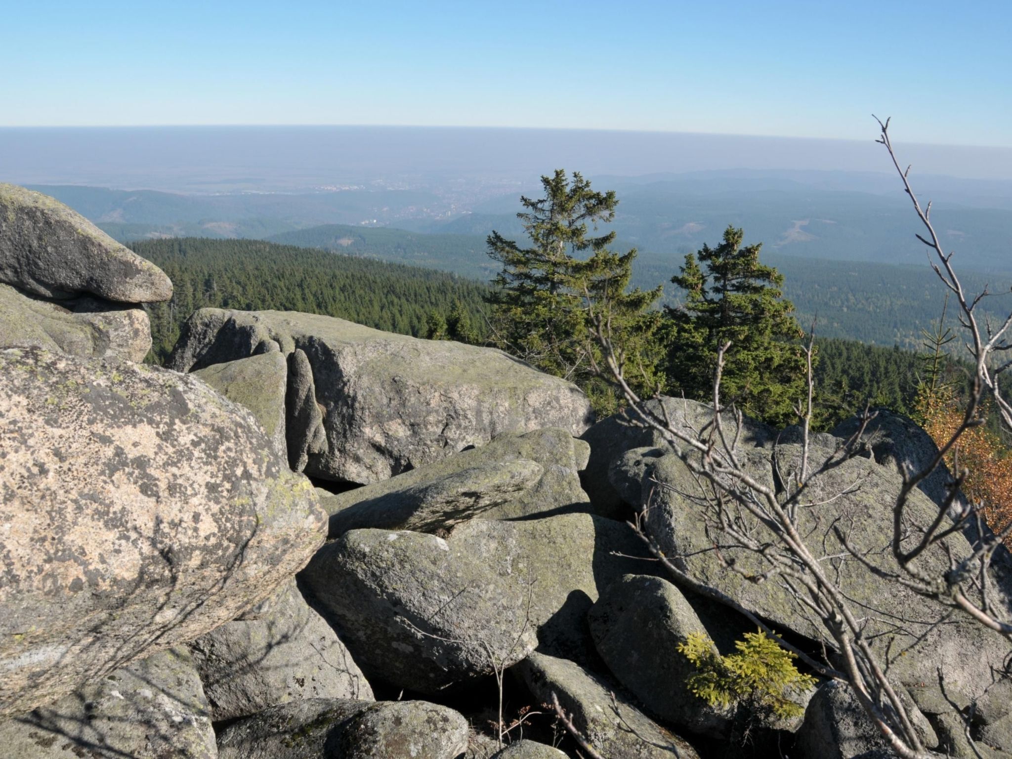 A rocky landscape with large boulders and a view of distant forested hills.