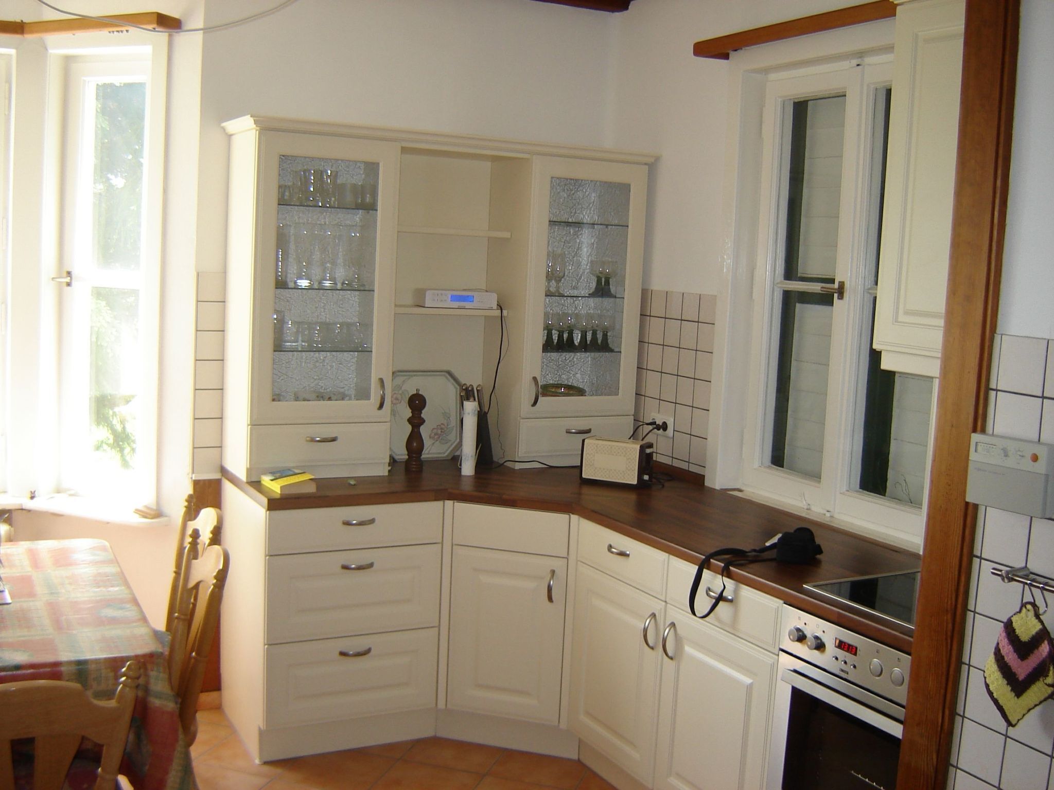 Une cuisine avec des armoires blanches, un plan de travail en bois, une fenêtre et un pare-feu en carrelage.