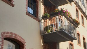 A multi-story building with brick facades, large windows, and balconies with flower boxes. - App.2  Speicherwerk by Interhome (Quedlinburg)