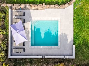 An aerial view of a swimming pool with a stone border, surrounded by a patio area with chairs and an umbrella. - Ein gemütlicher Kokon im Süden der Ardèche by Interhome (Largentière)