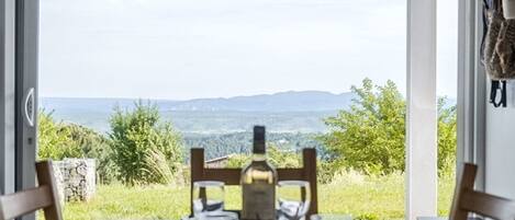 A dining table set for two with a view of a mountainous landscape.
