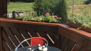 Een klein terras buiten met een ronde tafel en twee stoelen.