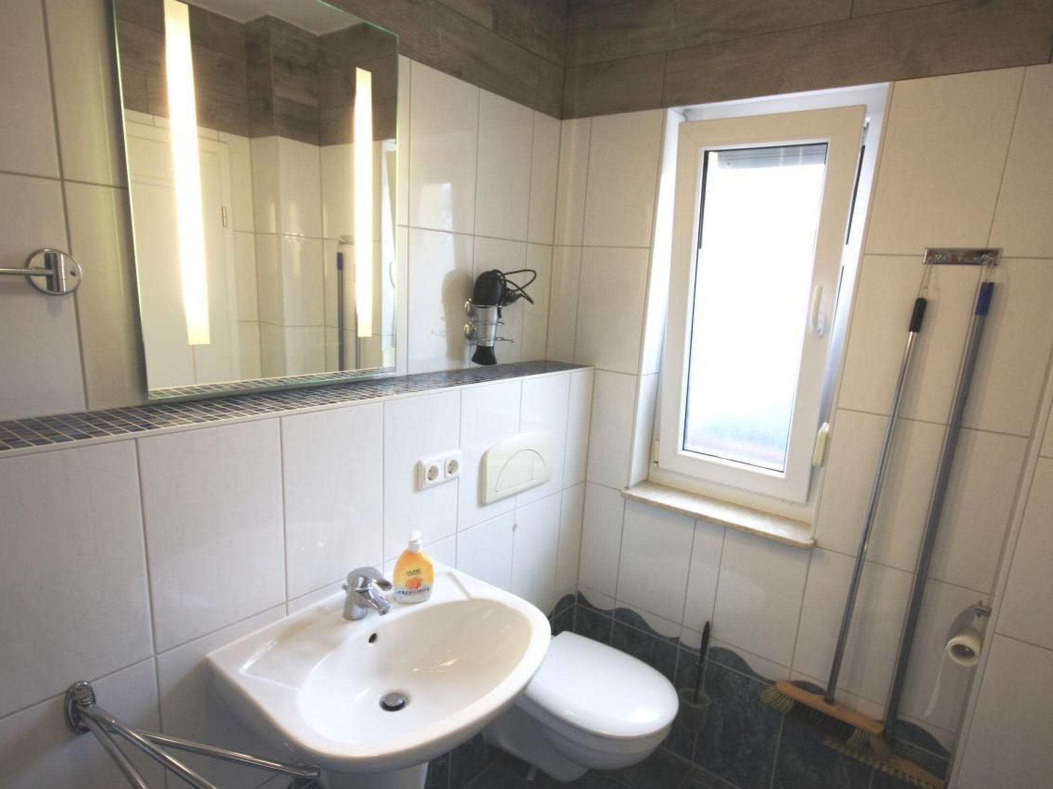 A bathroom with a sink, toilet, and a window.