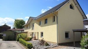 Een gebouw met twee verdiepingen, een gele gevel, meerdere ramen en een pannendak.