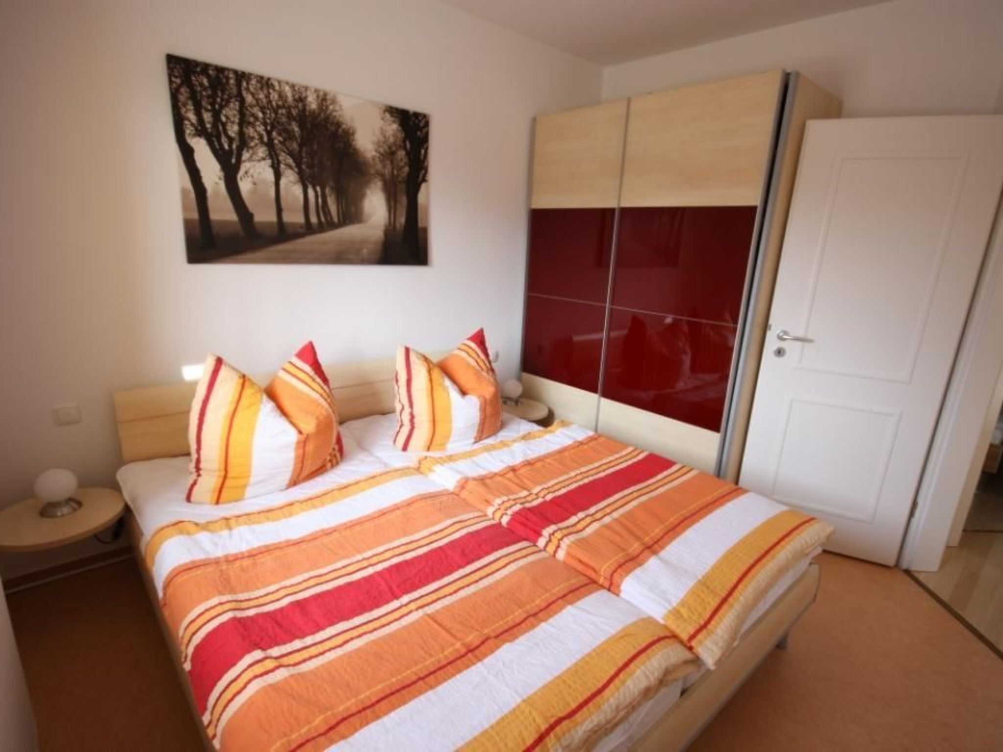 Ein Schlafzimmer mit einem Bett, einem Nachttisch, einem roten Kleiderschrank und einem Bild an der Wand.