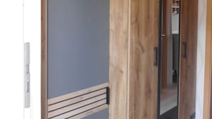 A room with a wooden wardrobe, a mirror, and a partially visible door. - Apartment  by Interhome (Diemelsee)