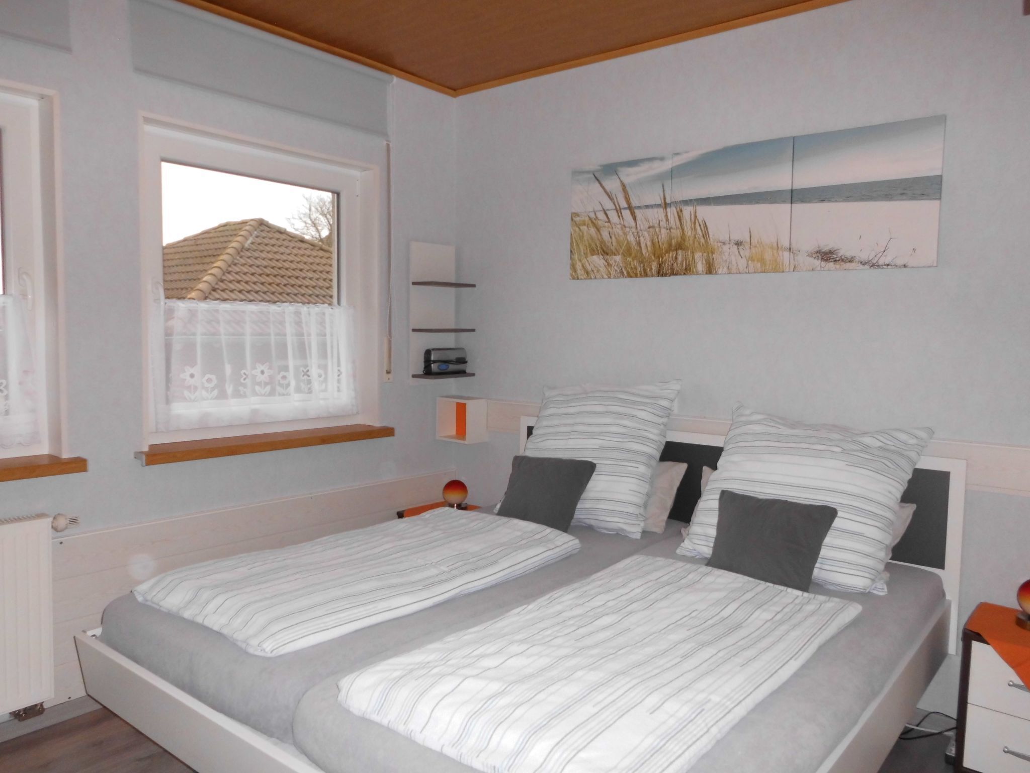 Una camera da letto con un letto, due comodini, una finestra e una mensola a parete.