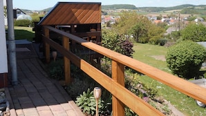 A wooden deck with a view of a rural landscape, including houses and hills. - Apartment  by Interhome (Diemelsee)