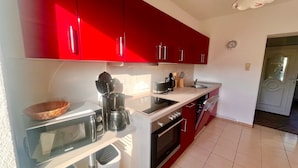 Una cucina moderna con mobili rossi, un forno a microonde, una macchina da caffè e un lavello.