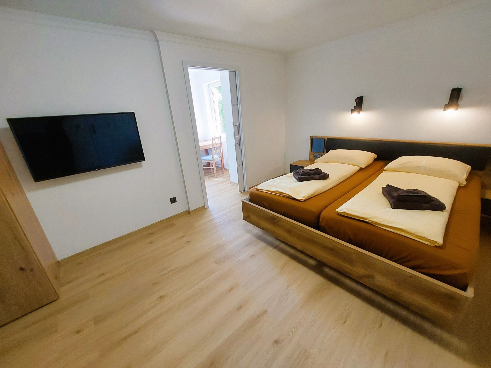 Ein Schlafzimmer mit Bett, Fernseher und einer Tür, die auf einen Balkon führt.