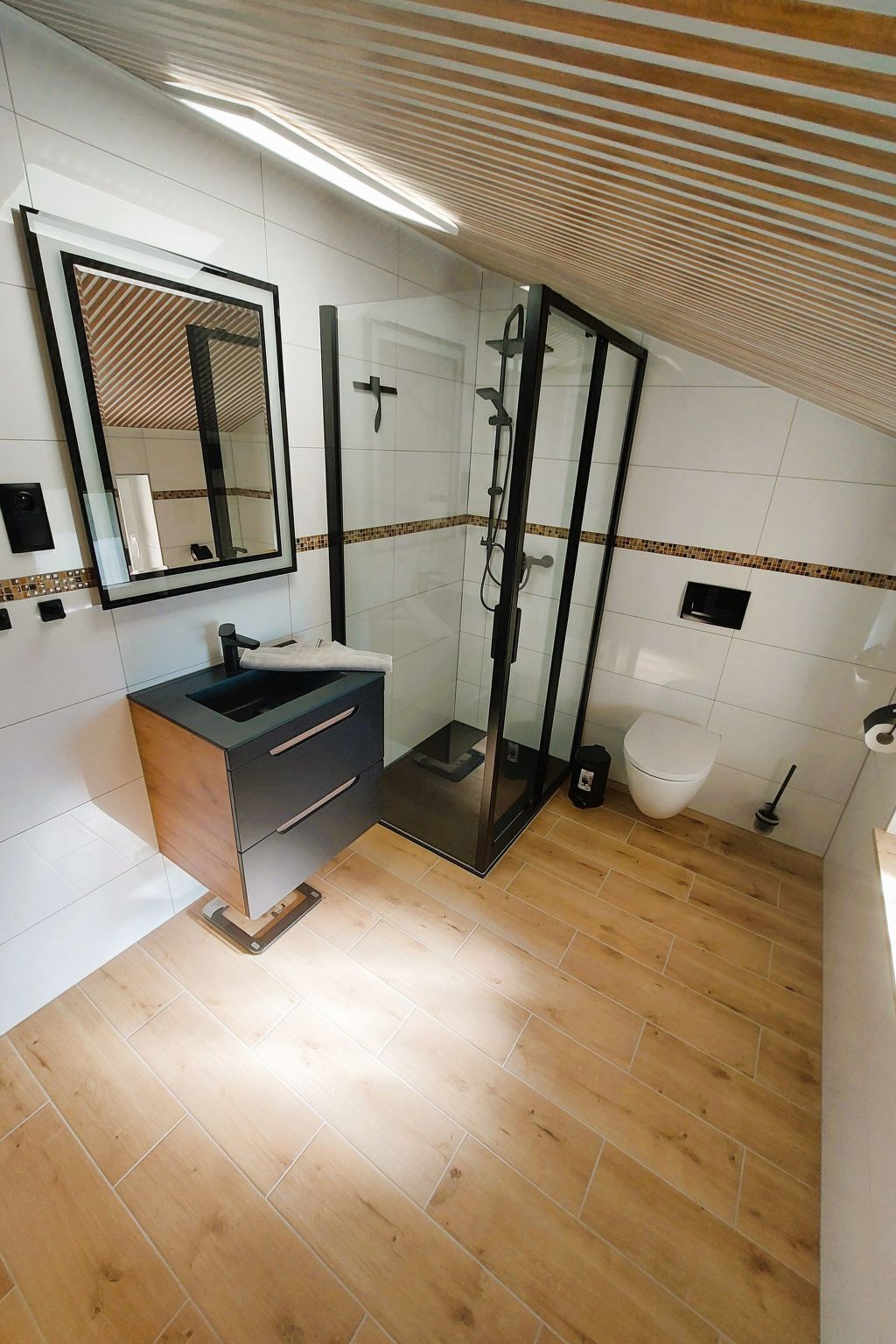 Ein modernes Badezimmer mit Duschkabine aus Glas, Waschtisch und Toilette.