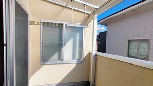 Un pasillo estrecho con una ventana y una puerta, un techo con una lámpara y una pared con una ventana.