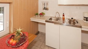 Een kleine keuken met een spoelbak, een koffiezetapparaat en een schaal fruit op het aanrecht.
