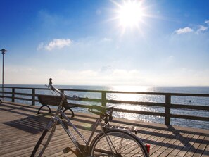 Eine Holzstege mit einem Fahrrad und einer Bank mit Blick auf ein Gewässer.