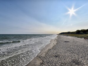 Ein Strand mit Wellen, blauem Himmel und Sonne.