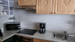 Een koelkast, een vaatwasser, kookgerei, borden en bestek
