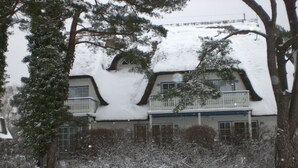 Una casa cubierta de nieve con un diseño arquitectónico singular, que incluye un techo curvo y un balcón.