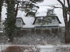 A snow-covered house with a unique architectural design, including a curved roof and a balcony. - Appartement Achtern-Diek-am-Strand in Zingst by Interhome (Ostseebad Zingst)
